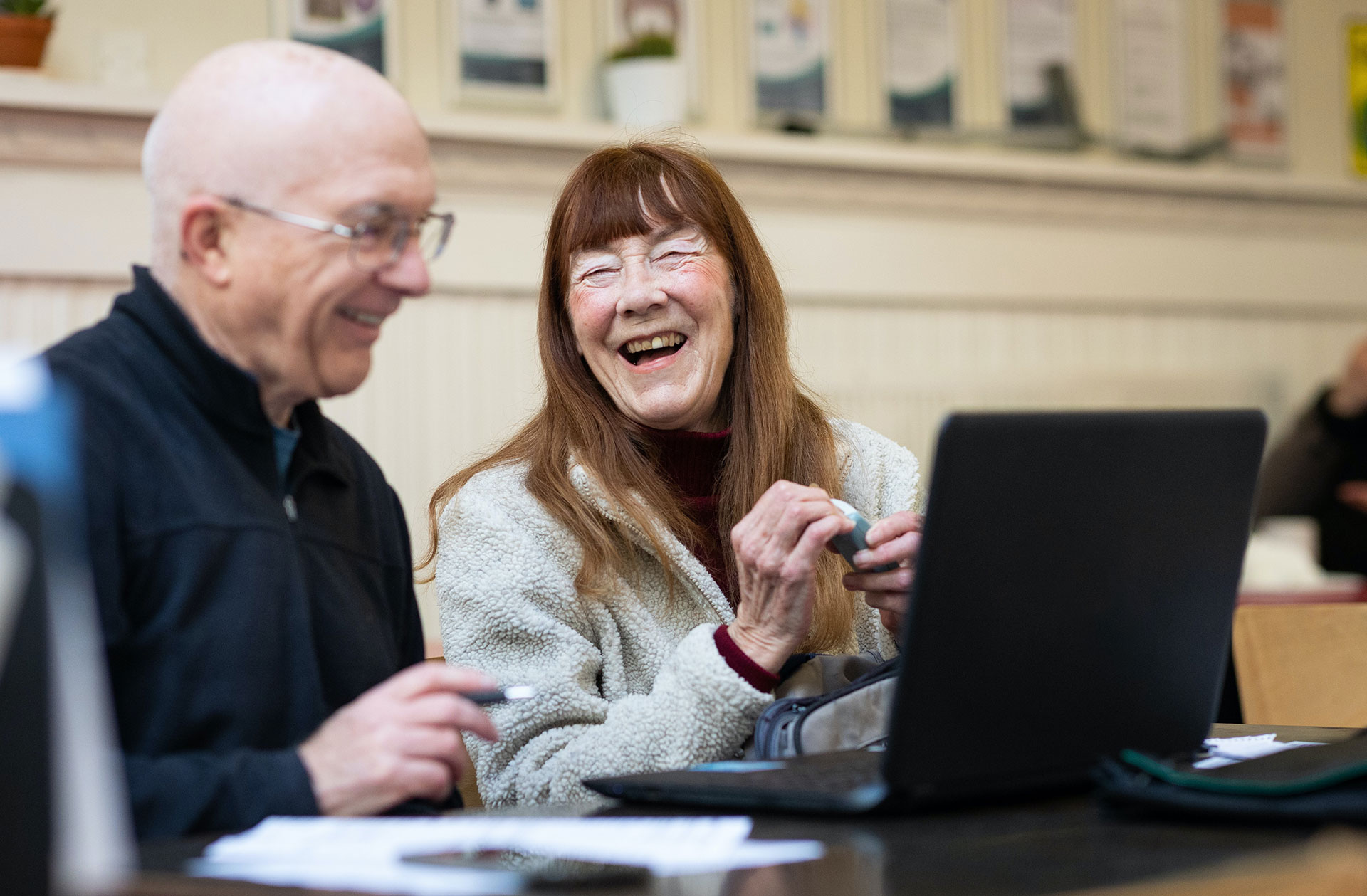 Zwei Senioren sitzen fröhlich vor einem Computer